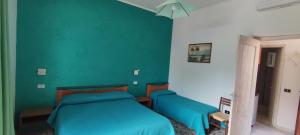 a bedroom with two beds and a blue wall at Chiaia Apartments by Caseaponza it in Ponza