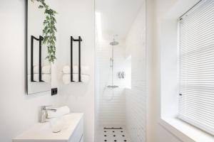 a white bathroom with a sink and a shower at Villa Zomerrust in De Panne