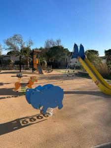 un parque infantil con un oso azul y un tobogán en Les mobil homes de NOLY Draps inclus ,TV ,Clim, en Port-la-Nouvelle