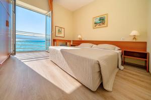 a bedroom with a large bed and a large window at Hotel Dobrovit ex Tamaris in Baška