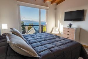 1 dormitorio con cama grande y ventana grande en Lagos del Sur en San Carlos de Bariloche