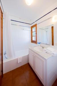 uma casa de banho branca com um lavatório e uma banheira em Duplex Es Brucs em Cala Morell