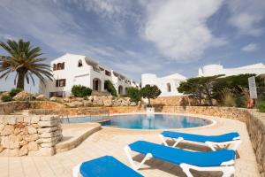 une villa avec une piscine et deux chaises longues dans l'établissement Duplex Es Brucs, à Cala Morell