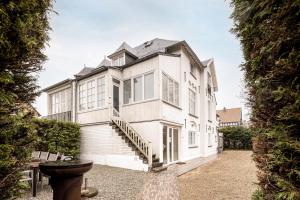 a large white house with a staircase in front of it at Villa Zomerrust in De Panne