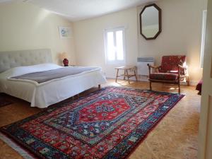 ein Schlafzimmer mit einem Bett, einem Teppich und einem Stuhl in der Unterkunft Maison Saloine in Saintes