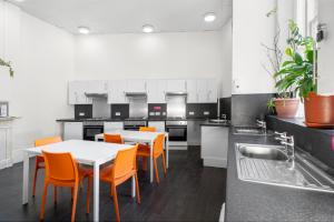 a kitchen with white tables and orange chairs at Halpin House (South Kensington) in London