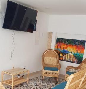 sala de estar con sillas de mimbre y TV en la pared en Casa Liz Hotel Boutique en Santa Marta