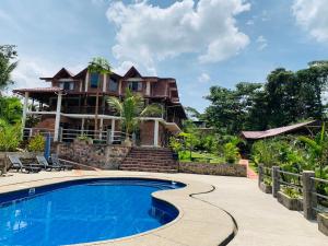a house with a swimming pool in front of a house at La Casa del Rio B&B in Puyo