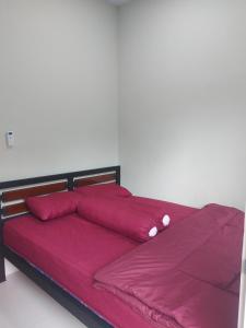 uma cama vermelha com lençóis e almofadas cor-de-rosa em GriyaQ Homestay em Kedungwaru