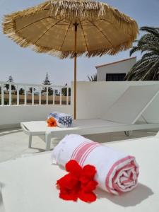 Piscina y Relax junto al Mar! في كوراليخو: طاولة بيضاء مع مظلة وزهور حمراء