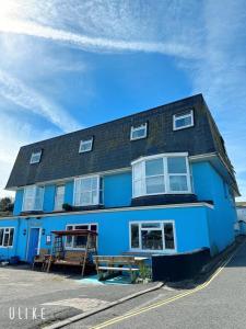 un bâtiment bleu avec un banc devant lui dans l'établissement Blue Room Hostel Newquay, à Newquay