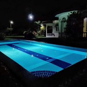 una piscina por la noche frente a una casa en My Excel Garden Deluxe Villa with Orchard and Pool, en Air Hangat