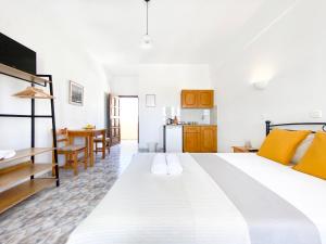 a bedroom with a large white bed and a kitchen at Almyra Villa in Perissa