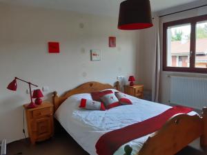 a bedroom with a bed with red pillows and a window at Au doux passage in Les Rousses