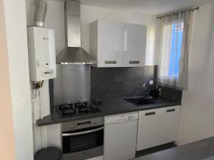 kuchnia z białymi szafkami i kuchenką w obiekcie Appartement proche centre ville w Aix-en-Provence