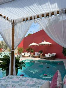 una piscina con toldo blanco y sombrillas en El Jardin de Gala en Castejón de Monegros
