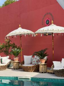 2 sombrillas y sillas junto a una piscina en El Jardin de Gala, en Castejón de Monegros