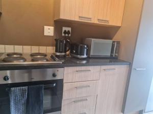 a kitchen counter with a stove and a microwave at Tripleg Apartments 1 in Fourways