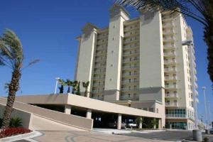 a large building with a palm tree in front of it at Crystal Shores 1301 by ALBVR - Beautiful Beachfront Corner Condo with Gorgeous Views! in Gulf Shores