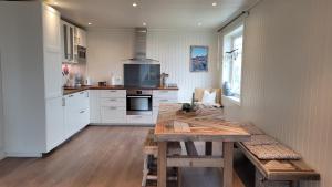 a kitchen with a wooden table and a counter top at Haramsøy Holiday Apartment- Island Life North in Haram