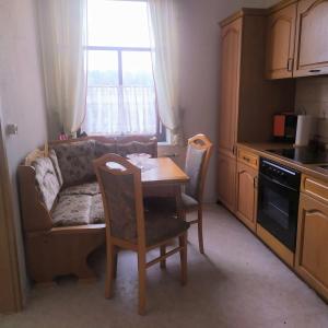 a living room with a table and a couch and a kitchen at Pension Stöß in Falkenstein