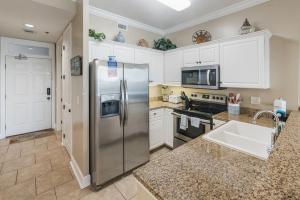 uma cozinha com um frigorífico de aço inoxidável e um lavatório em Island Royale 1002 by ALBVR - Come & relax at our beautiful beachfront condo in the heart of Gulf Shores! em Gulf Shores