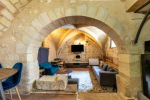 a living room with a couch and a tv in a stone wall at Les pieds dans le Château - Jacuzzi in Amboise