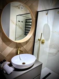 La salle de bains est pourvue d'un lavabo blanc et d'un miroir. dans l'établissement Słoneczny Apartament Oświęcim, à Oświęcim