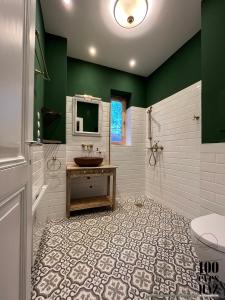 baño con lavabo, aseo y pared verde en 100 éves ház en Balatonakarattya
