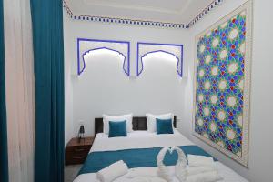 1 dormitorio con 1 cama de color azul y blanco en Jahangir Boutique Bukhara, en Bukhara