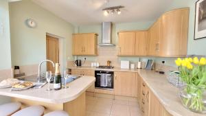 a large kitchen with wooden cabinets and a sink at Colenso St - 2 bed house by Bishy Road & River in York