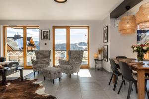 a living room with a table and chairs and windows at Apartament Czorsztyn in Kluszkowce