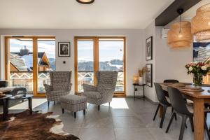 a living room with a table and chairs and windows at Apartament Czorsztyn in Kluszkowce