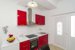a white kitchen with red cabinets and a window at Romantic studio apartment in Sobra