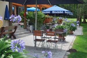 Wirtshaus Birkenhof في فايسنشتات: طاولة وكراسي مع مظلة وورود أرجوانية