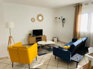 a living room with yellow and blue chairs and a table at T3 Spacieux lumineux, climatisé in Montpellier