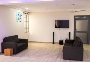 sala de estar con 2 sillas y TV de pantalla plana en THE GRANGE HOTEL GHANA, en Dawhwenya