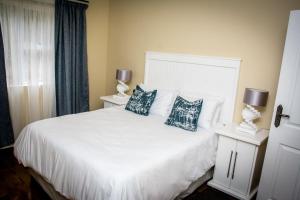 a bedroom with a white bed with two blue pillows at Ocean Breeze Beach House in Port Shepstone