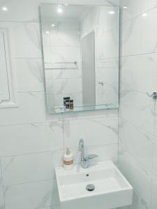 uma casa de banho branca com um lavatório e um espelho em VASO'S APARTMENTS em Tolo