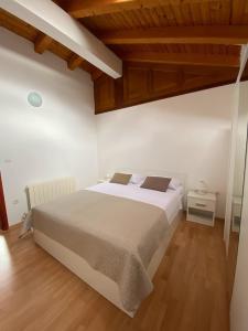 a bedroom with a large white bed and wooden floors at Apartman I&I in Peroj