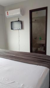 a bedroom with a white bed with a mirror at Apartamento Excelente Pé na Areia in Guaratuba