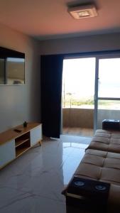 a living room with a bed and a large window at Apartamento Excelente Pé na Areia in Guaratuba