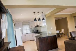 a kitchen with white cabinets and a black counter top at Ocean Breeze Beach House in Port Shepstone