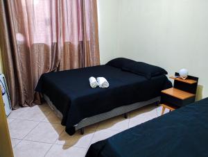 a bedroom with a bed with two shoes on it at Quarto Aconchegante Completo in Cruzeiro