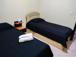 two beds sitting next to each other in a room at Quarto Aconchegante Completo in Cruzeiro