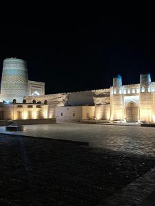 um grande edifício com luzes acesas à noite em Feruzkhan Hotel - Madrassah Mohammed Rakhim Khan 1871 em Khiva