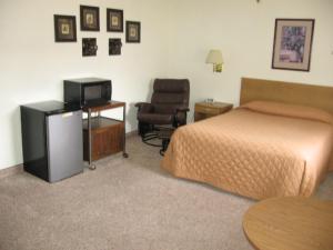 a bedroom with a bed and a television and a chair at Little Bear Motel in Green River