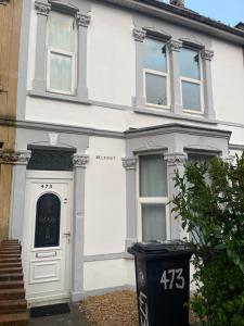 a white house with a door and a trash can at Perfect room 1 in Bristol