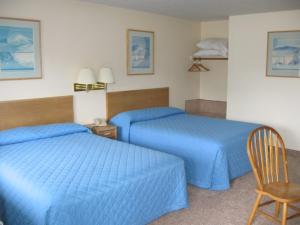 una habitación de hotel con 2 camas azules y una silla en Little Bear Motel en Green River