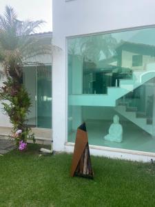 a glass house with a statue sitting on the grass at Casa de praia mangaratiba in Mangaratiba